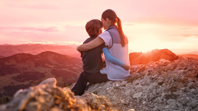 Una madre è seduta con il suo bambino sulla cima di una montagna. Il bambino indossa una manica a compressione. Una madre è seduta con il suo bambino sulla cima di una montagna. Il bambino indossa una manica a compressione.
