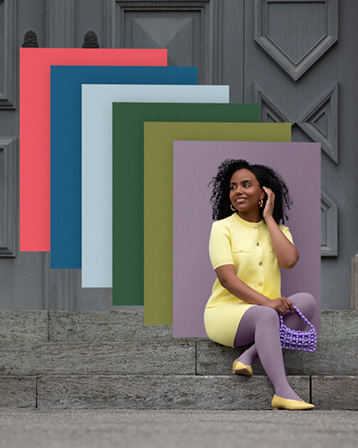 Una mujer con medias de compresión en color Cozy Violet está sentada en unas escaleras. Al fondo, los paneles de color de la actual colección Juzo Trend Colours. Una mujer con medias de compresión en color Cozy Violet está sentada en unas escaleras. Al fondo, los paneles de color de la actual colección Juzo Trend Colours.