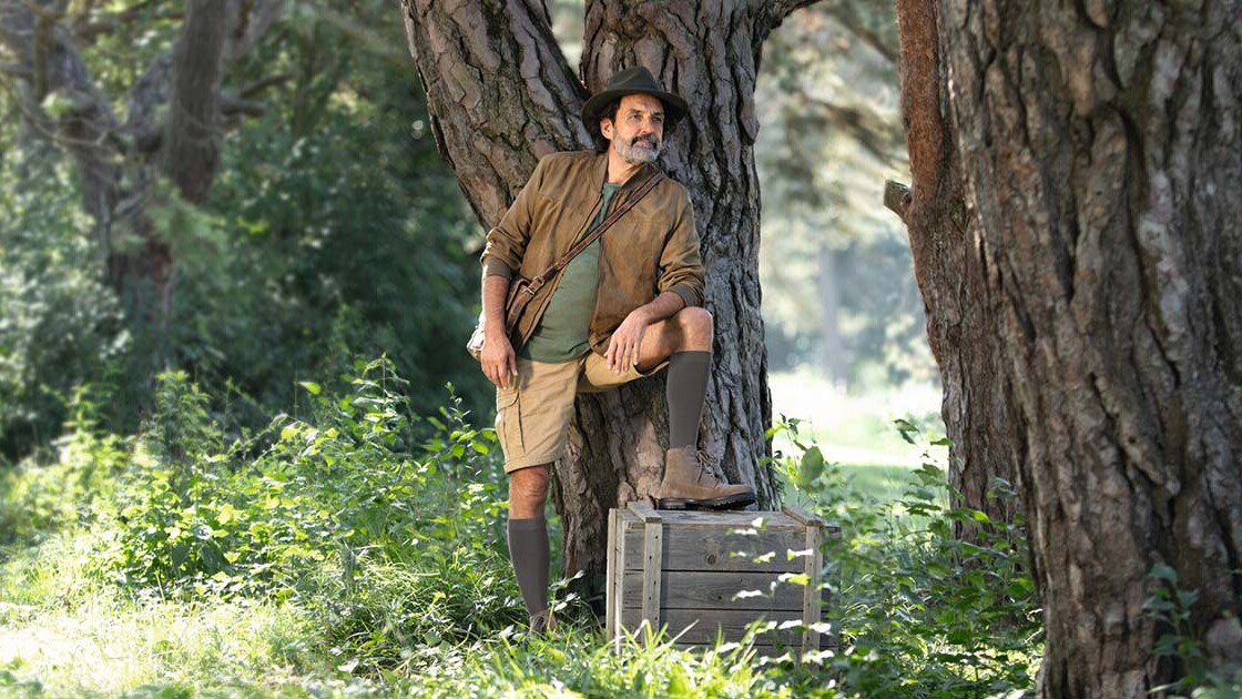 Um homem com um fato de explorador está na natureza e olha para longe. Tem calças de compressão até ao joelho. Um homem com um fato de explorador está na natureza e olha para longe. Tem calças de compressão até ao joelho.