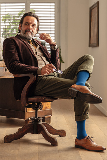 3. Lifestyle image Juzo Adventure Man wears the Juzo Adventure in blueberry and sits at his desk