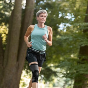 JuzoPro Patella Xtec Plus Frau im Wald beim Joggen mit Patella Xtex Plus Bandage