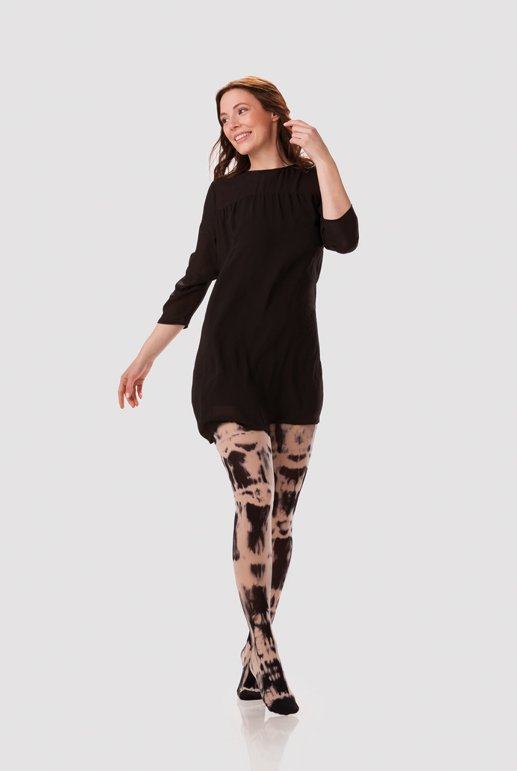 A woman is wearing a black long-sleeved dress with a compression garment in black and sesame batik A woman is wearing a black long-sleeved dress with a compression garment in black and sesame batik
