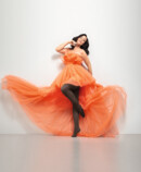 Lifestyle Bild Juzo Inspiration Frau mit Juzo Inspiration und Strumpfhose in Kakao und orangenem Kleid