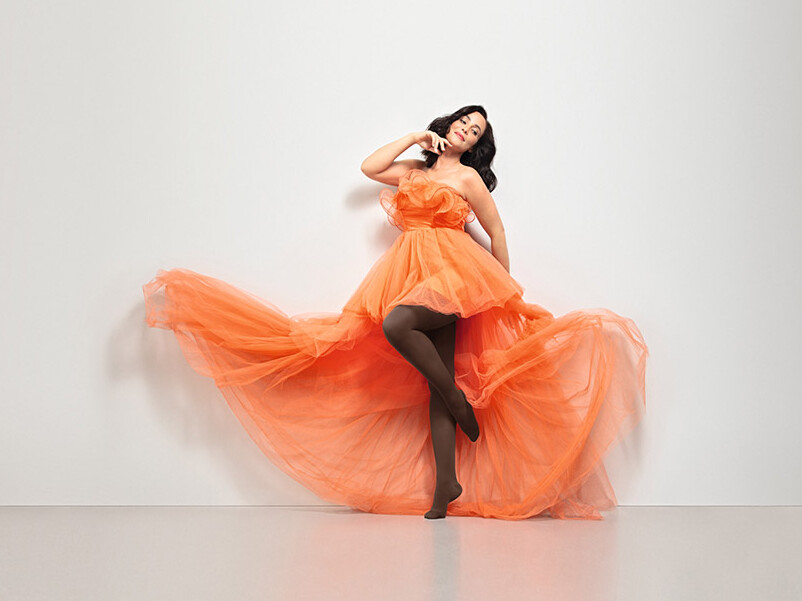 Juzo Inspiration A woman is wearing an orange tulle dress and Juzo Inspiration in cocoa