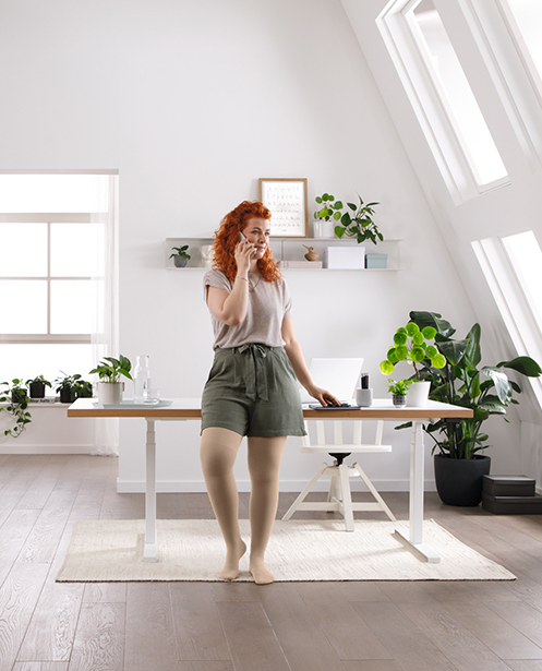 A woman is standing at her desk, talking on the phone A woman is standing at her desk, talking on the phone