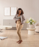 Eine dunkelhaarige Frau schließt gerade den Reißverschluss der Juzo Comprima Leggins