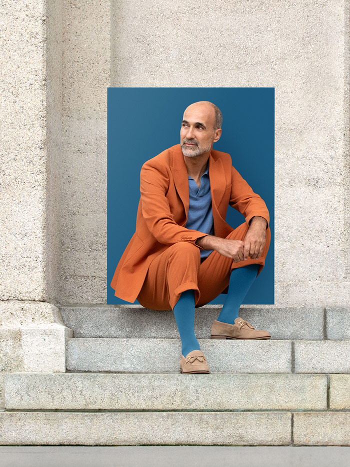 Casual Blue A man sits on steps in the city wearing a Casual Blue compression garment with a relaxed orange suit