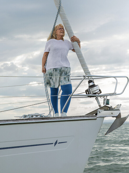 A woman with lymphoedema is standing on the deck of a boat. She is wearing blue compression stockings A woman with lymphoedema is standing on the deck of a boat. She is wearing blue compression stockings
