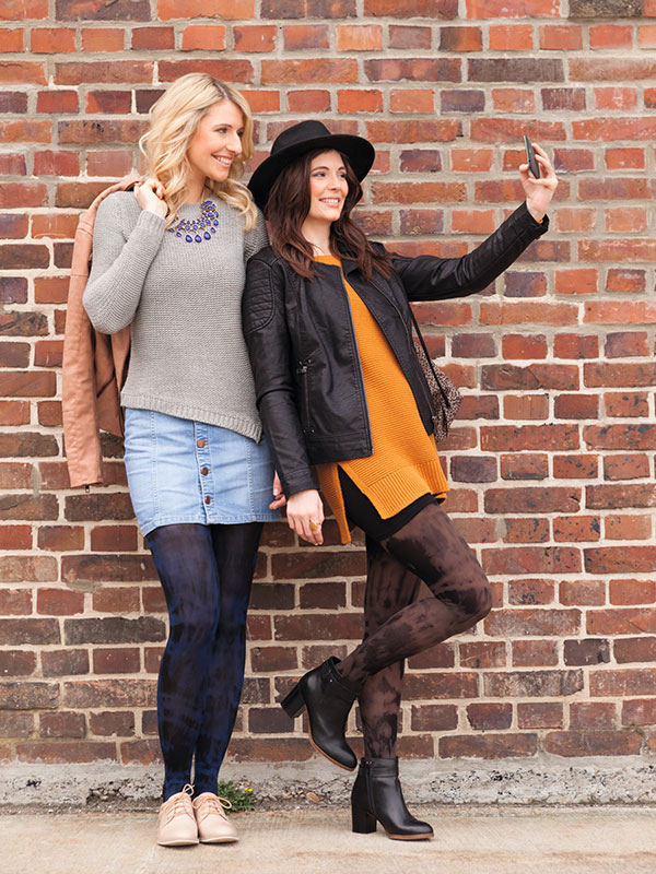 Two women leaning against a wall. They are wearing compression stockings with batik pattern